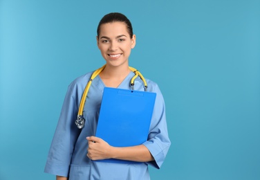Photo of Portrait of young medical assistant with stethoscope and clipboard on color background. Space for text