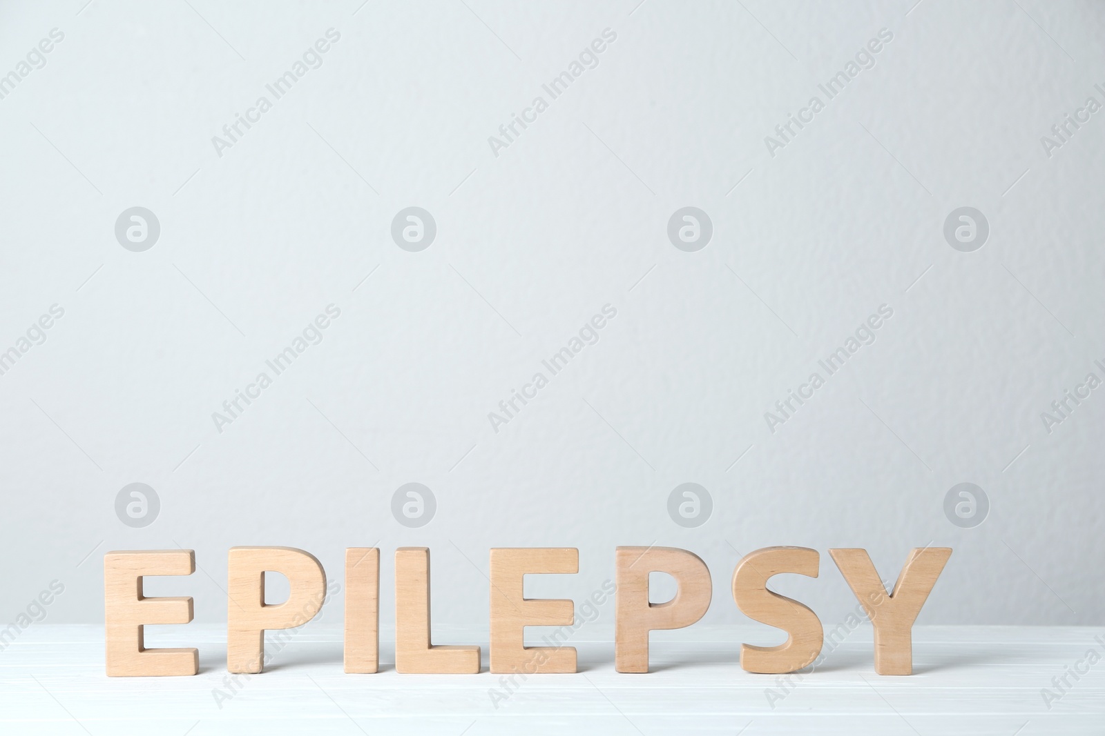 Photo of Word Epilepsy made of wooden letters on white table. Space for text