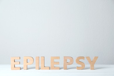 Photo of Word Epilepsy made of wooden letters on white table. Space for text