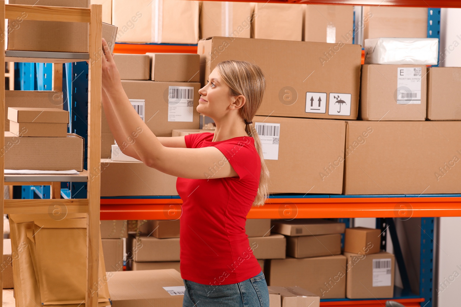 Photo of Post office worker near rack with parcels indoors