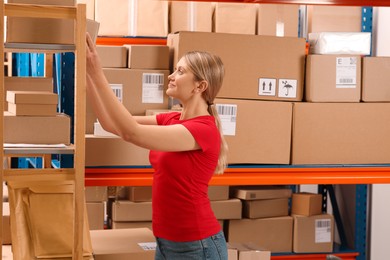 Post office worker near rack with parcels indoors