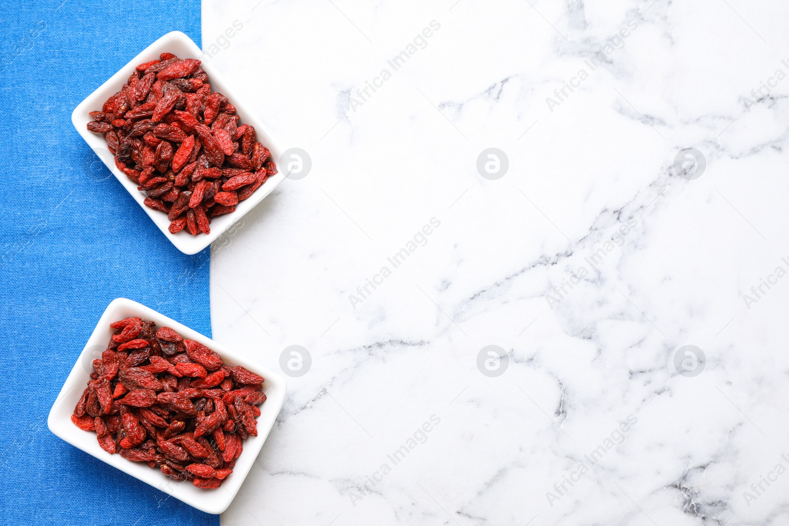 Photo of Dry goji berries on marble table, flat lay. Space for text