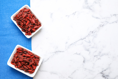 Photo of Dry goji berries on marble table, flat lay. Space for text