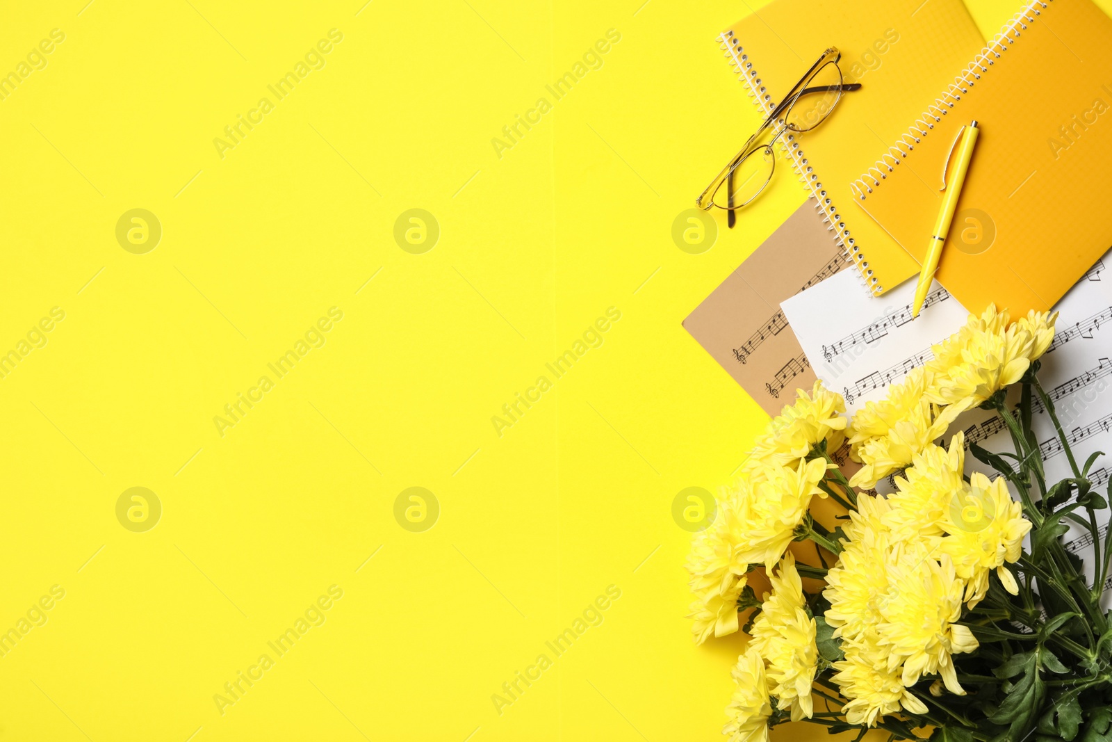 Photo of Flat lay composition with flowers and stationery on yellow background, space for text. Teacher's day