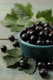 Ripe blackcurrants and leaves on wooden rustic table, closeup