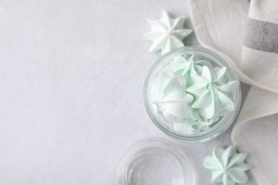 Photo of Tasty meringue cookies in glass jar on light grey table, top view. Space for text