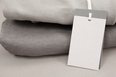 Garment with cardboard tag on kraft paper sheet, closeup. Space for text