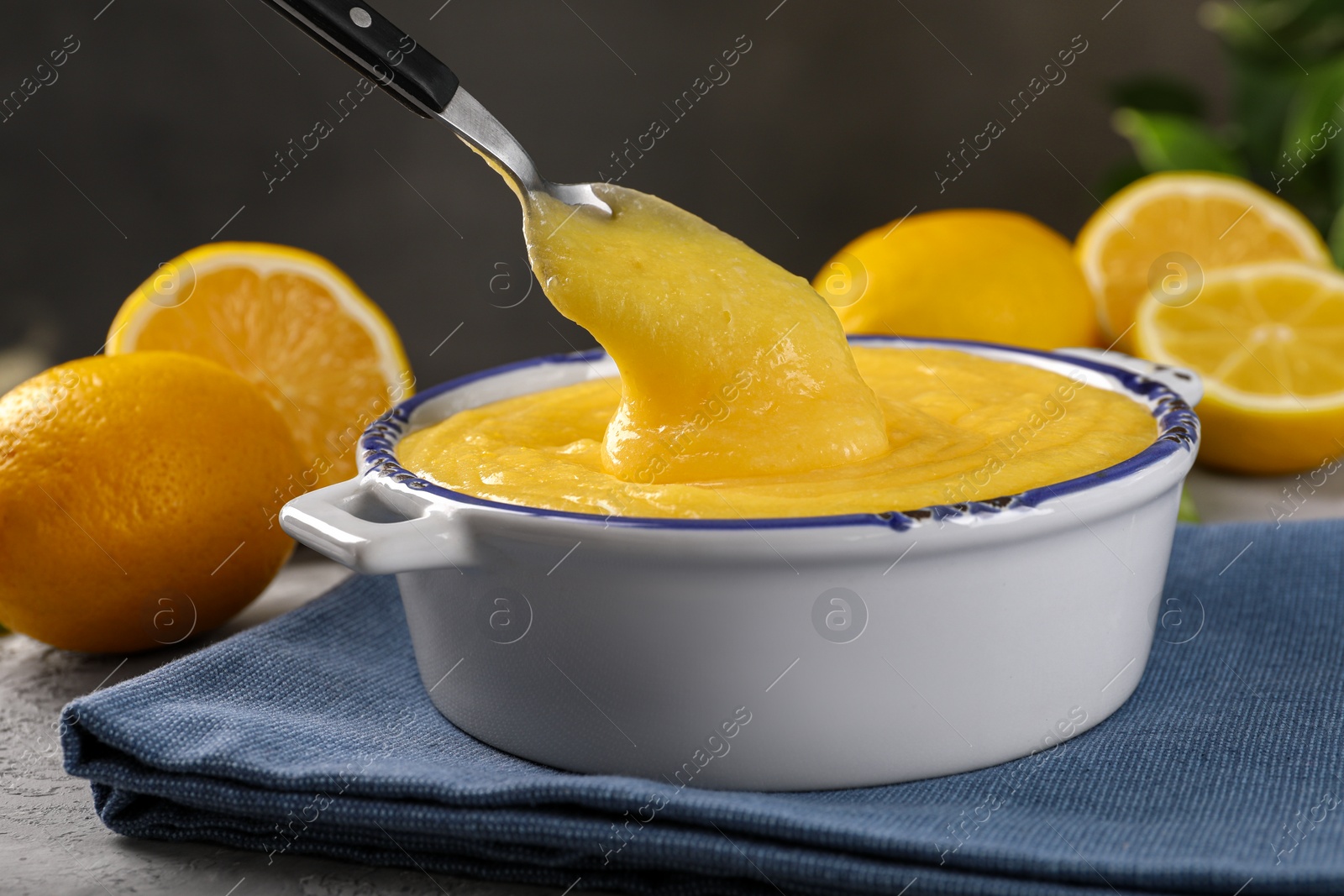 Photo of Taking delicious lemon curd from bowl at table, closeup