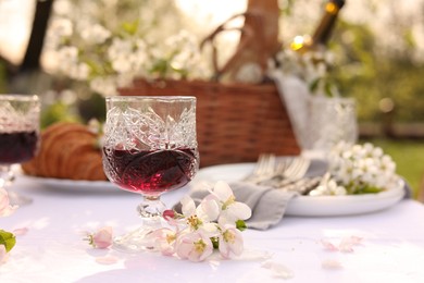 Stylish table setting with beautiful spring flowers, wine and croissants in garden