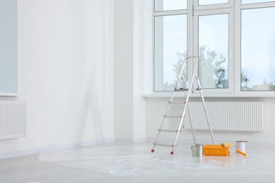 Stepladder and painting tools near window in empty room, space for text
