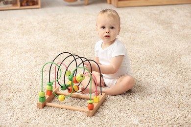 Photo of Children toys. Cute little boy playing with bead maze on rug at home