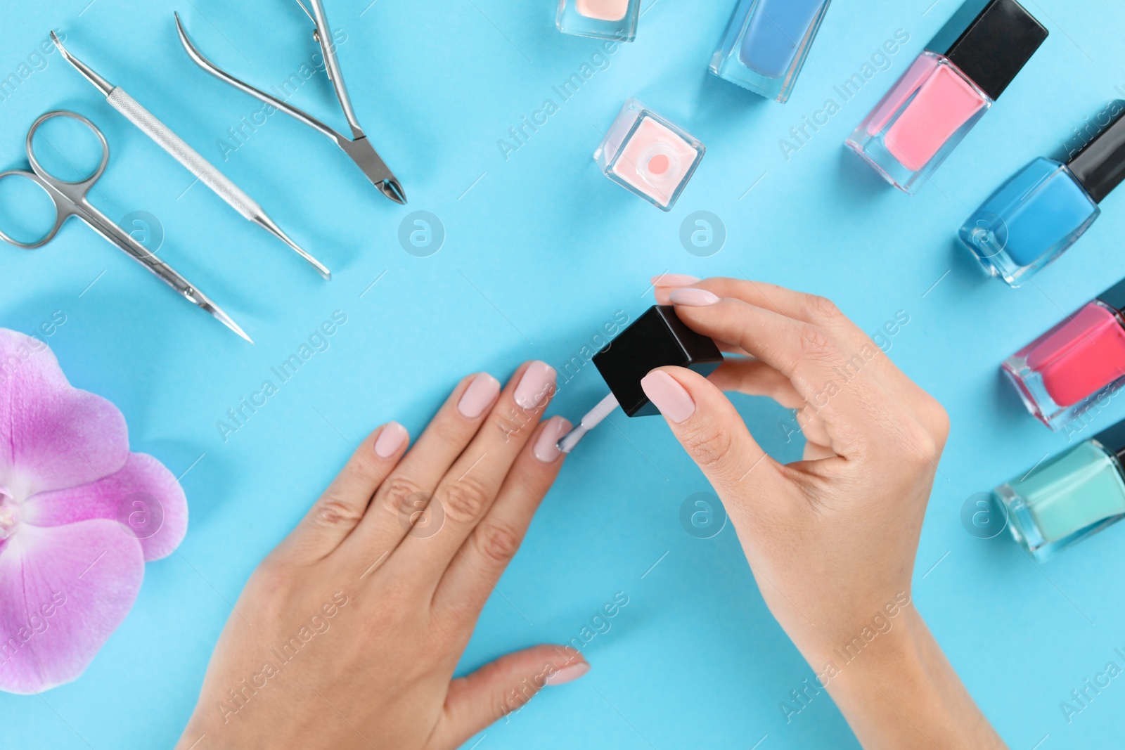 Photo of Woman applying nail polish on color background, above view