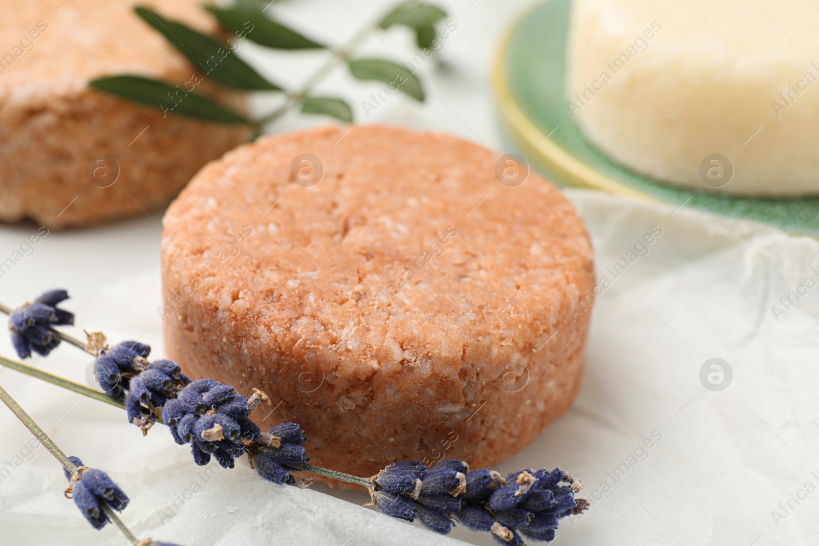 Photo of Solid shampoo bar and lavender on light table, closeup