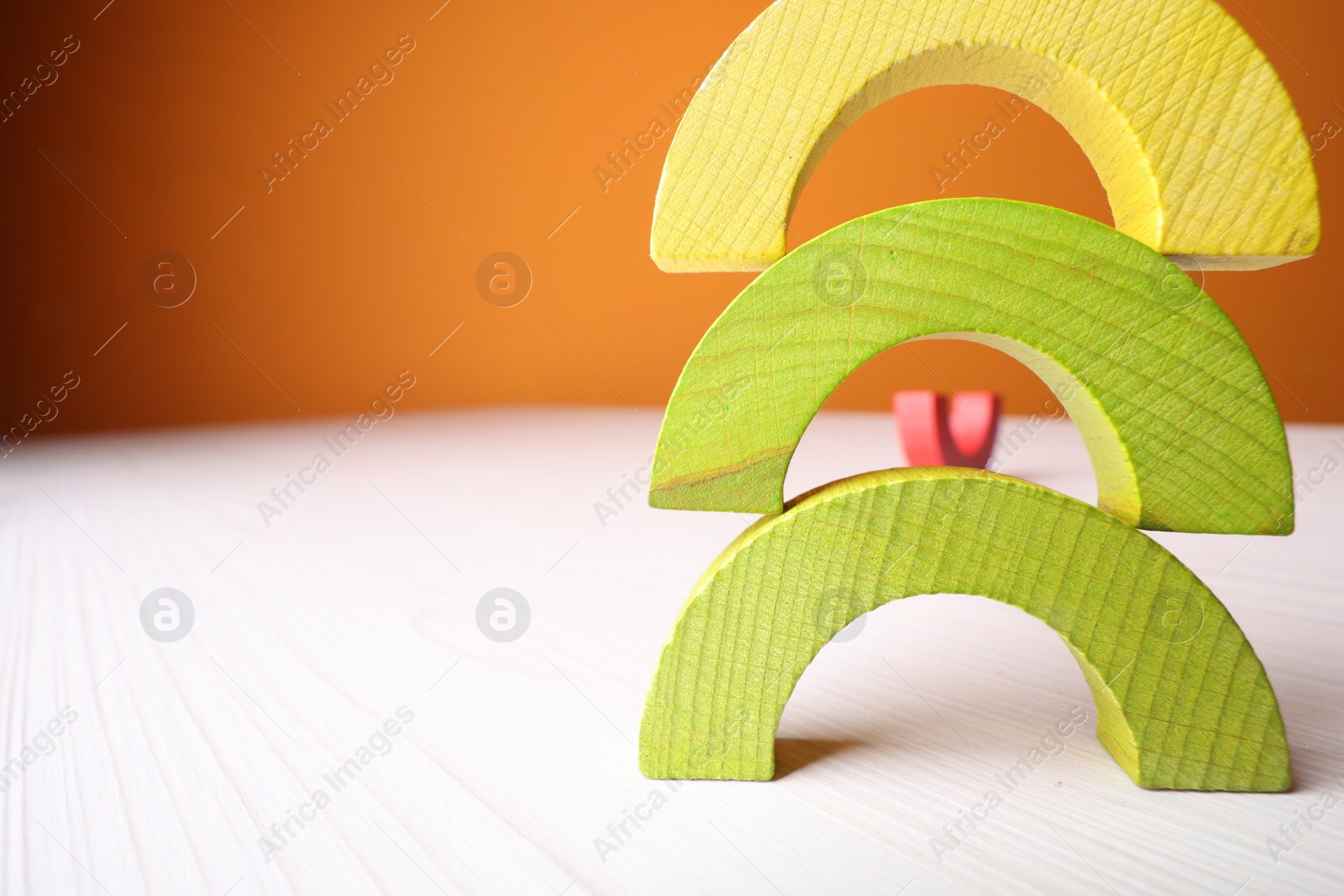 Photo of Colorful wooden pieces of educational toy on light table, closeup and space for text. Motor skills development