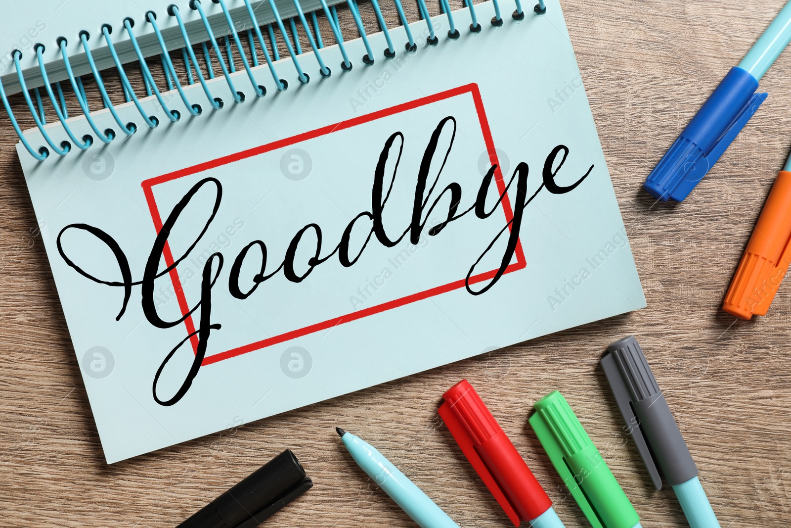 Image of Notebook with word Goodbye and markers on wooden table, flat lay