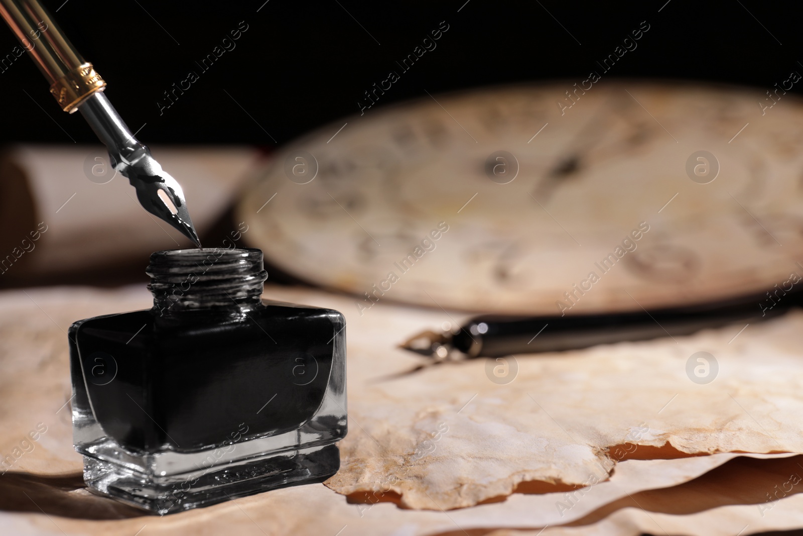 Photo of Inkwell with fountain pen on vintage parchment, closeup. Space for text