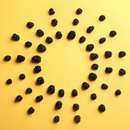 Frame made with fresh blackberries on yellow background, top view. Space for text