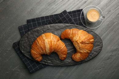 Delicious fresh croissants and cup of coffee on gray table, flat lay