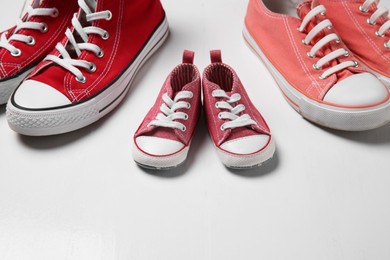 Photo of Stylish sneakers for all family members on white wooden background