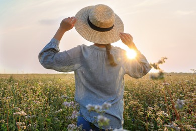 Photo of Woman with hat in beautiful blossoming buckwheat field