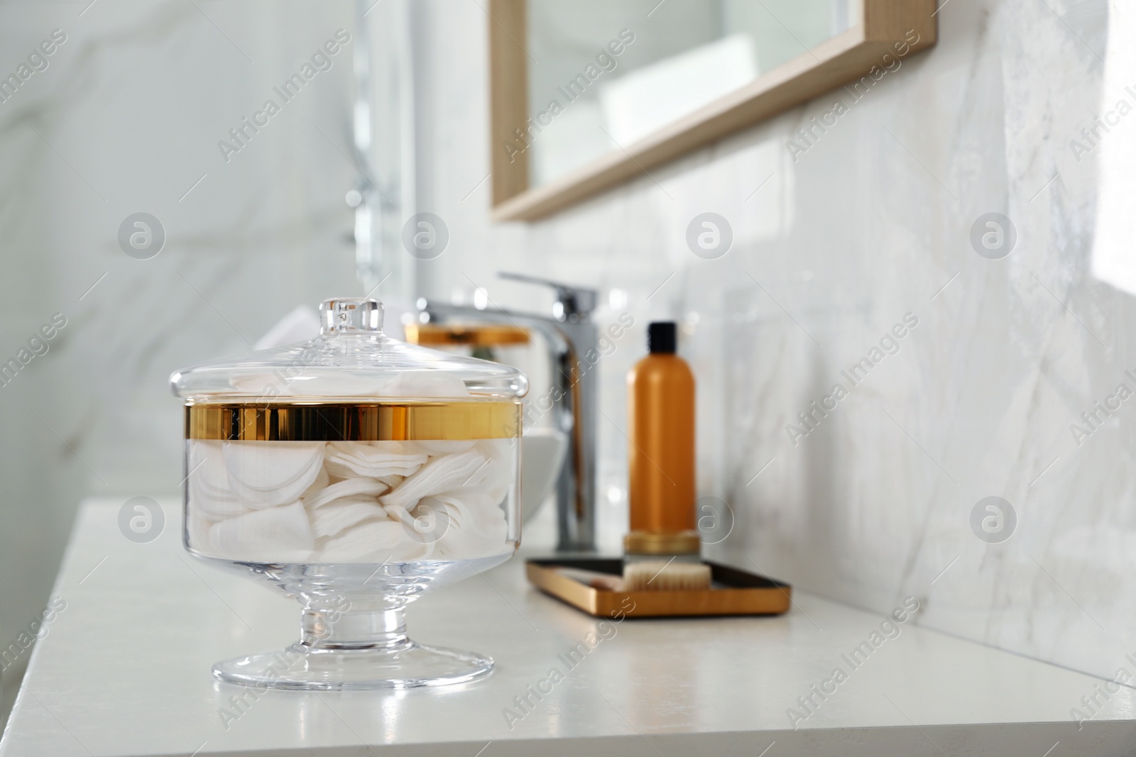 Photo of Jar with cotton pads on bathroom countertop