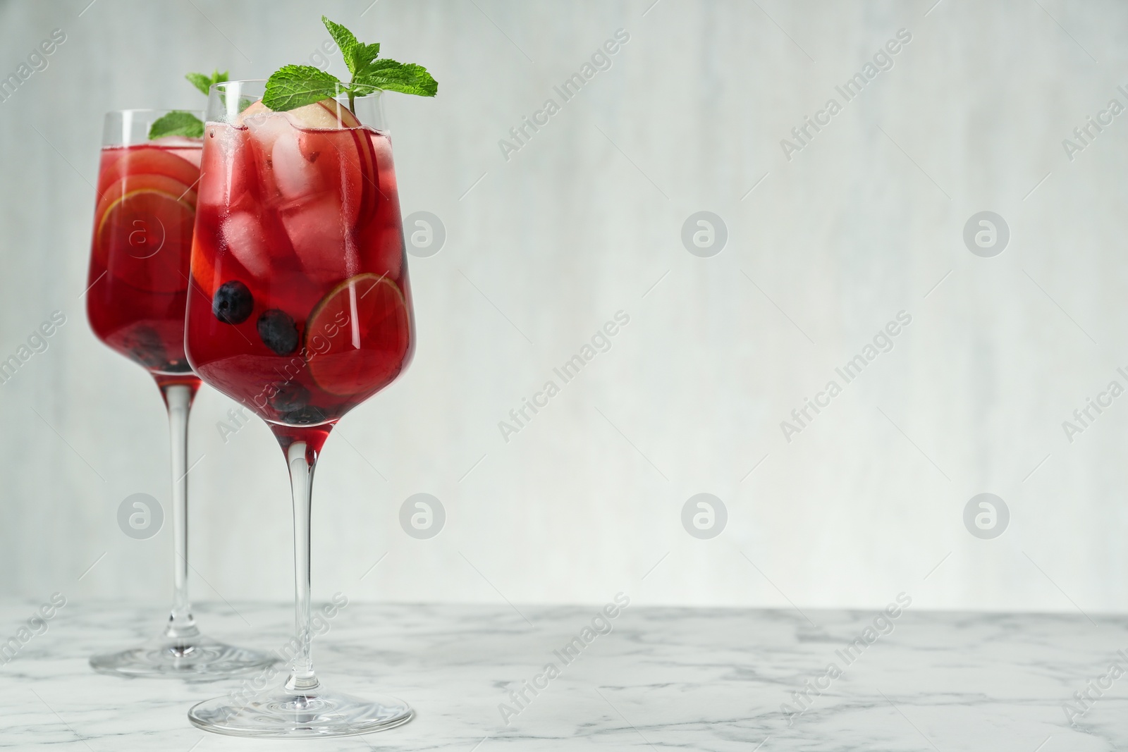 Photo of Delicious Red Sangria with fruits on white marble table, space for text