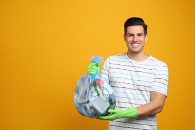 Photo of Man holding full garbage bag on yellow background. Space for text