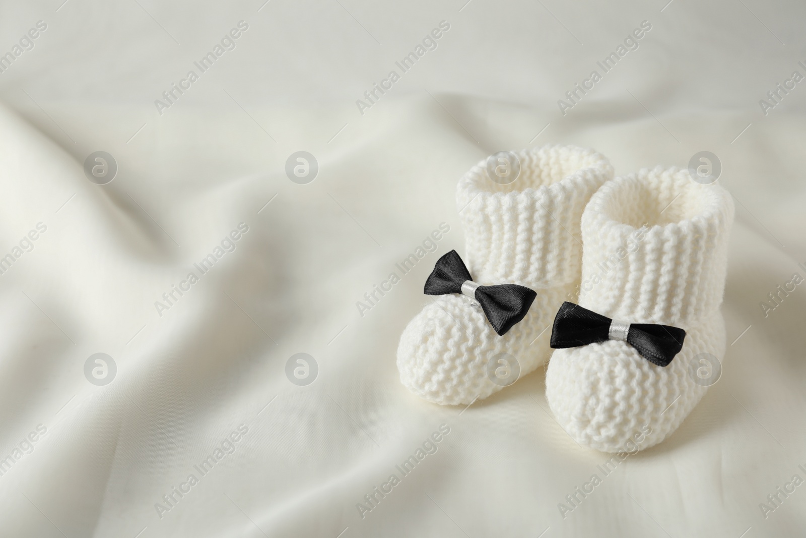 Photo of Handmade baby booties on light plaid. Space for text