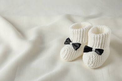 Handmade baby booties on light plaid. Space for text