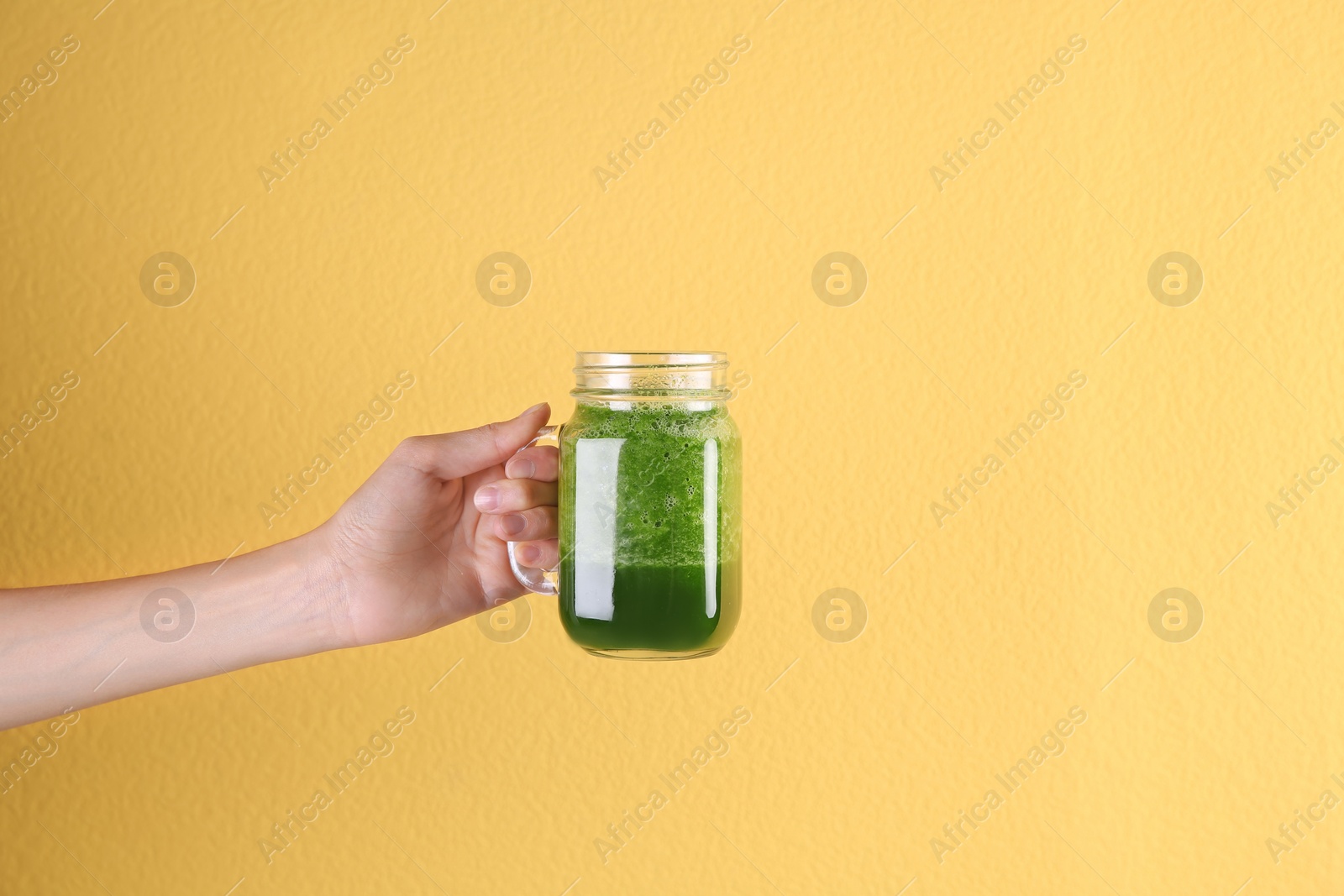 Photo of Young woman holding mason jar of healthy smoothie on color background