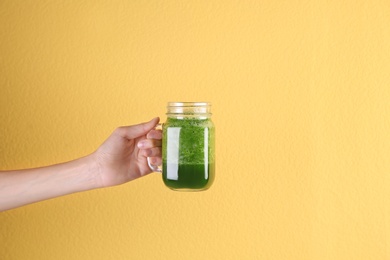 Photo of Young woman holding mason jar of healthy smoothie on color background