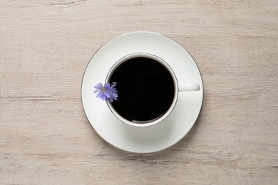 Photo of Cup of delicious chicory drink and flowers on light wooden table, top view