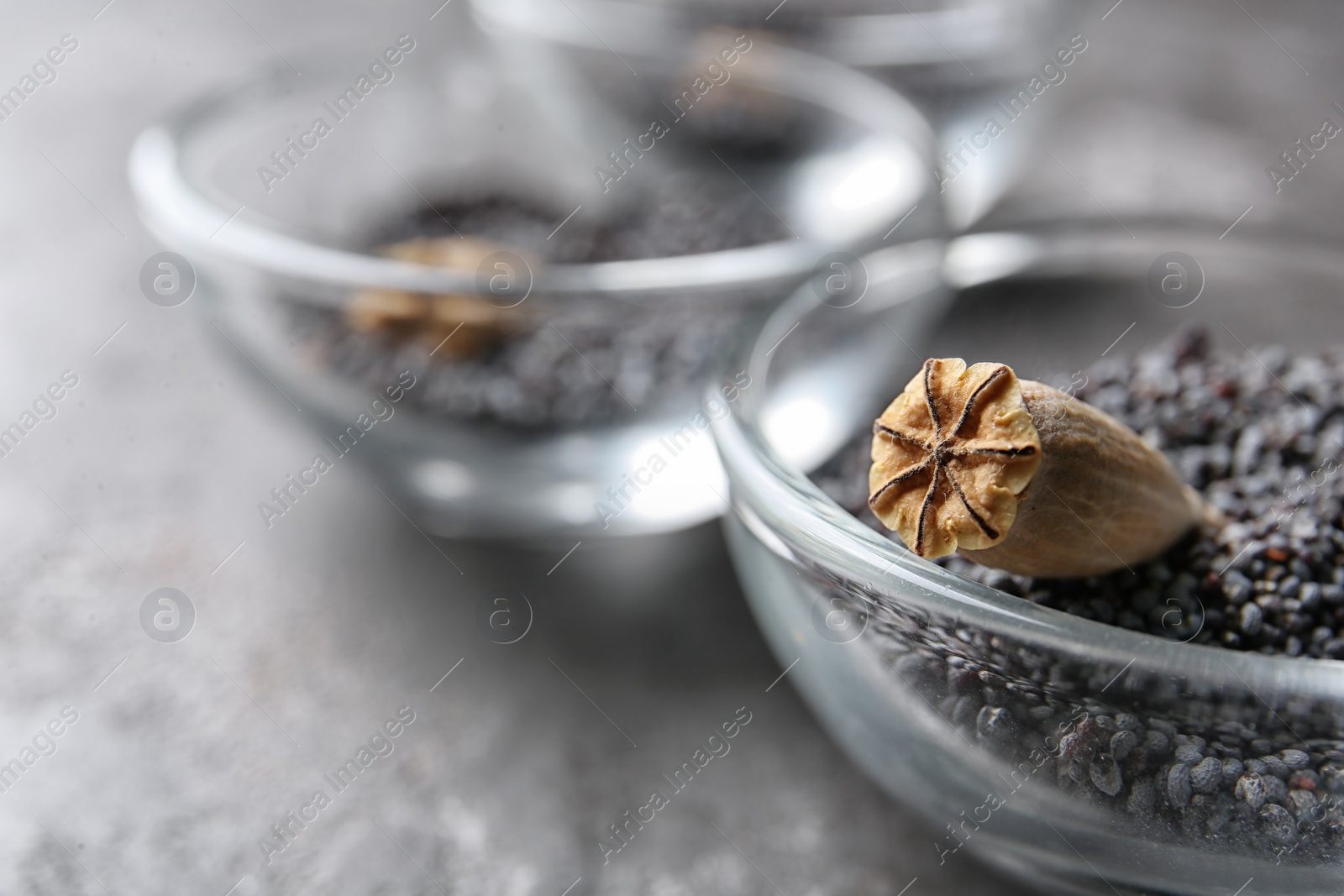 Photo of Bowl with dry poppy head and seeds on table, closeup