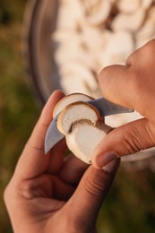 Photo of Man slicing freshly picked mushrooms outdoors, closeup