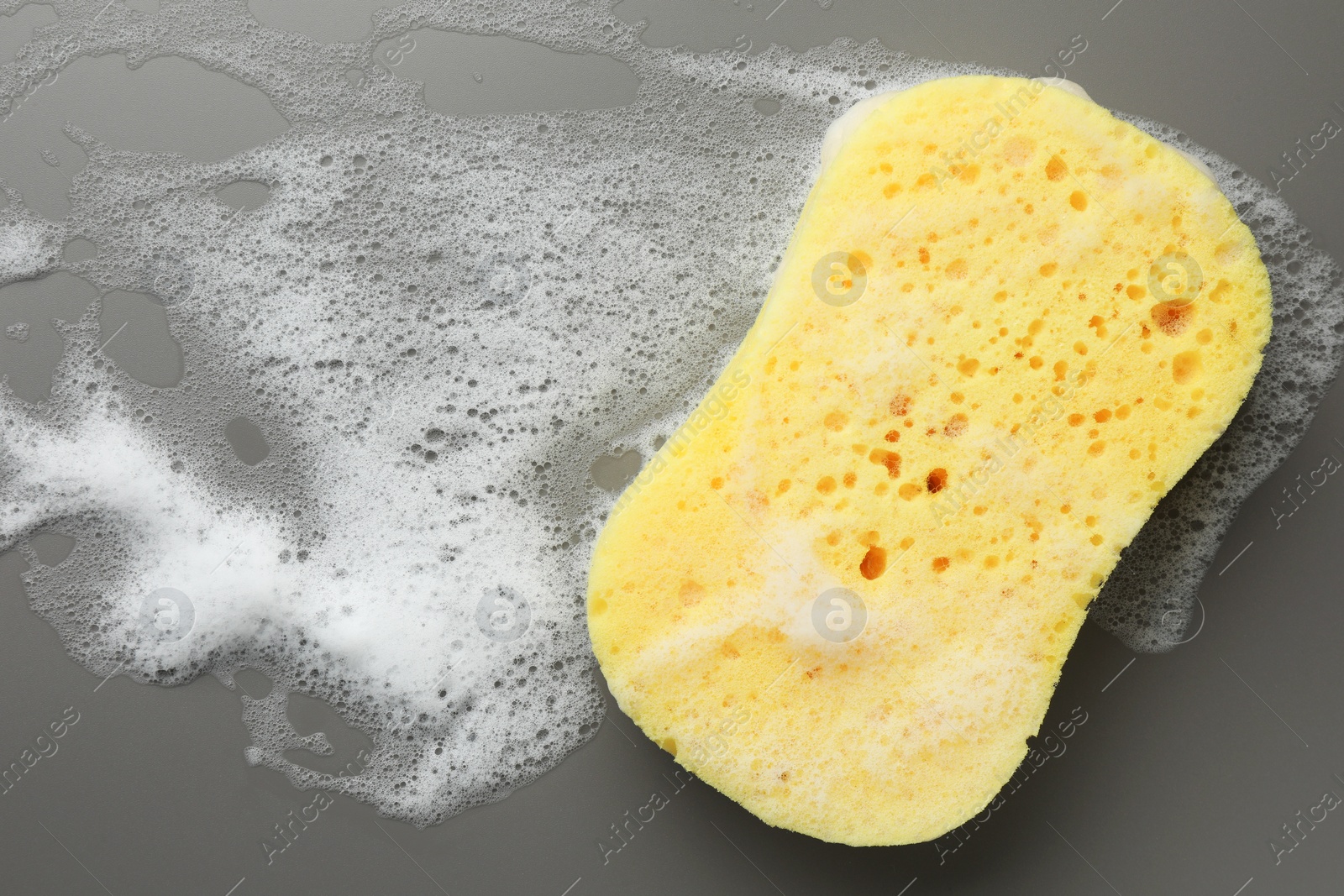 Photo of Yellow sponge with foam on grey background, top view