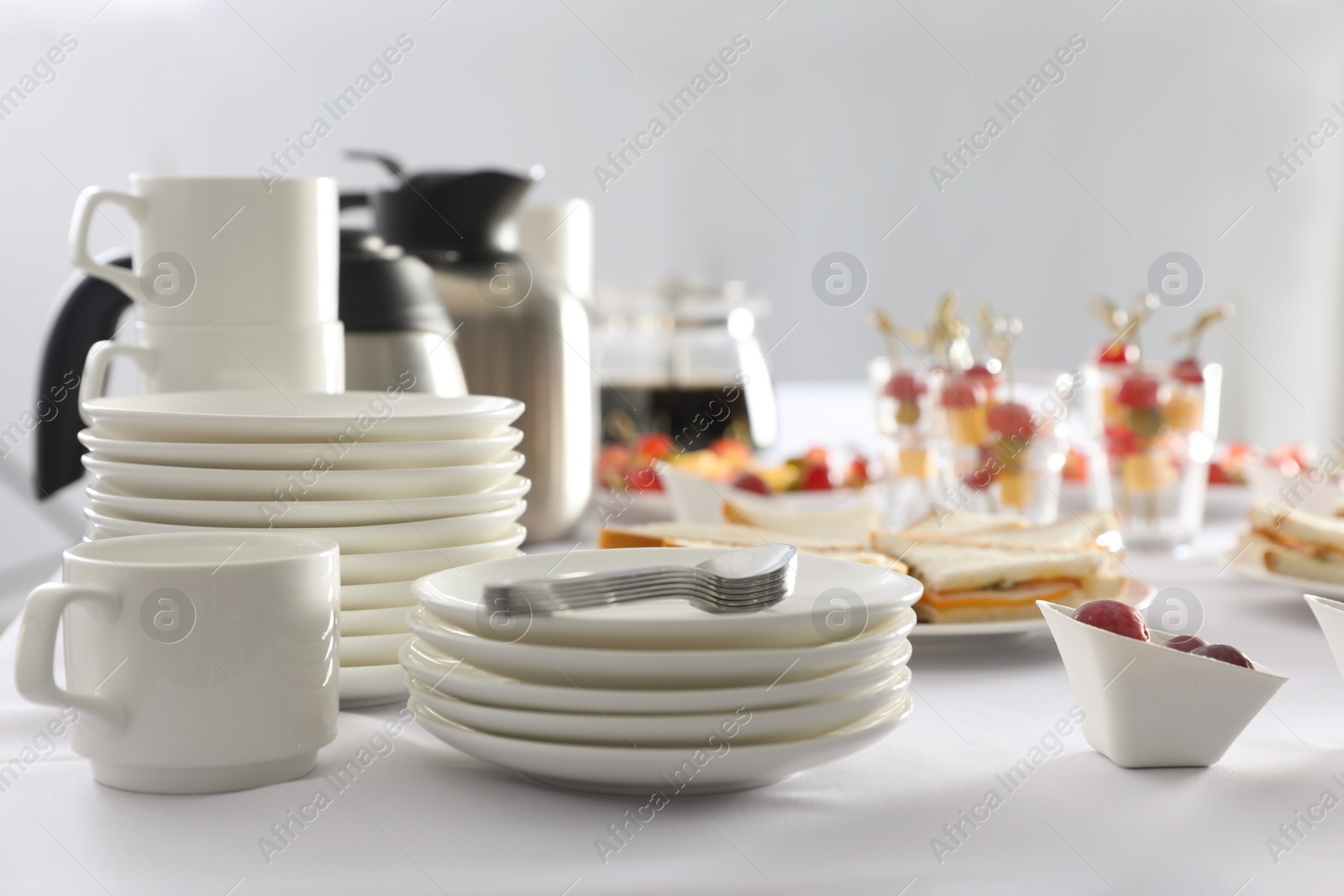 Photo of Table with different delicious snacks and dishware indoors. Coffee break