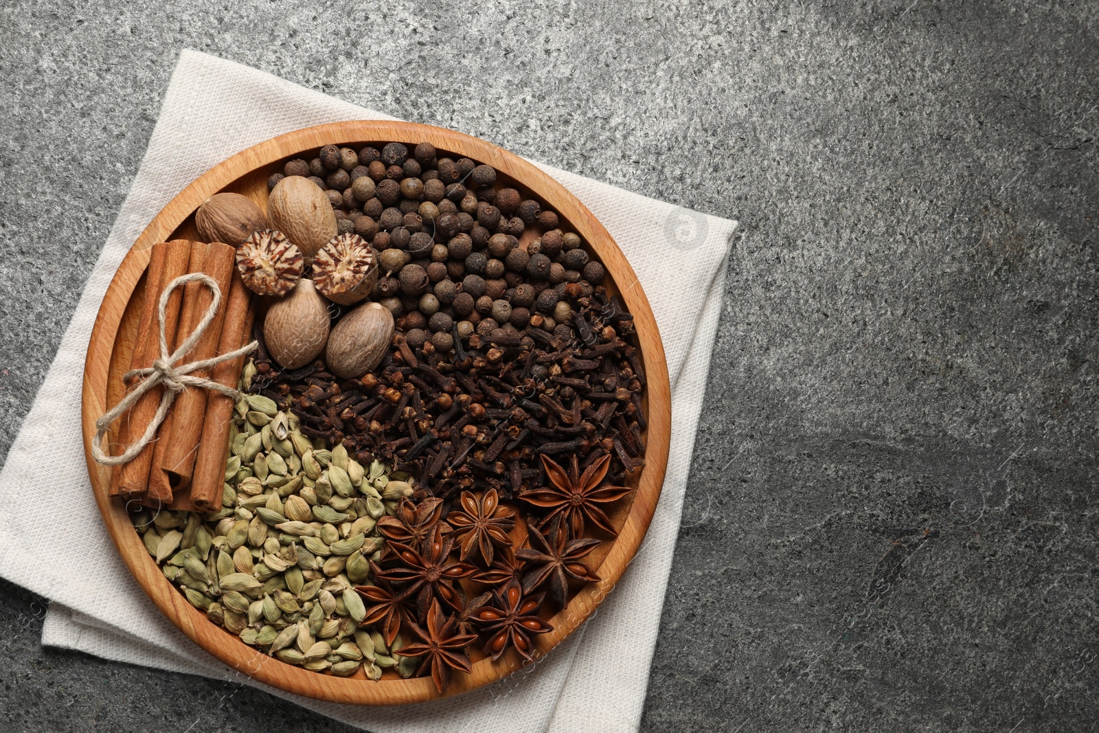 Photo of Different spices and nuts on gray textured table, top view. Space for text