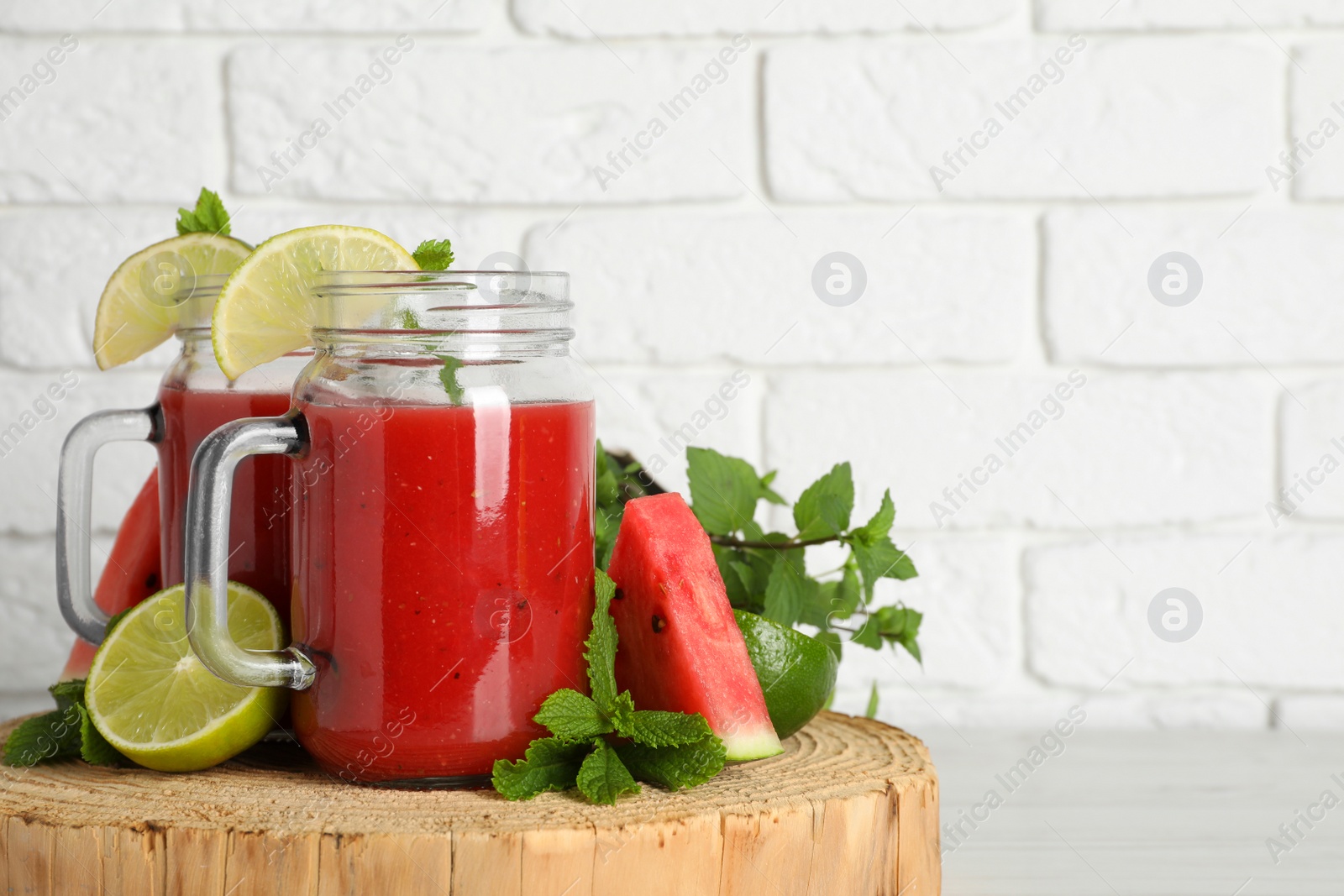 Photo of Tasty summer watermelon drink, limes and mint on white wooden table, space for text