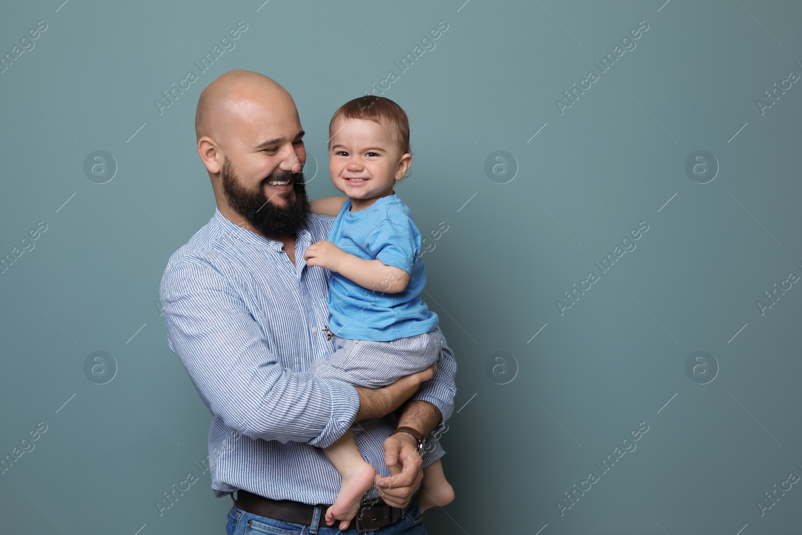 Photo of Portrait of dad and his little son on color background