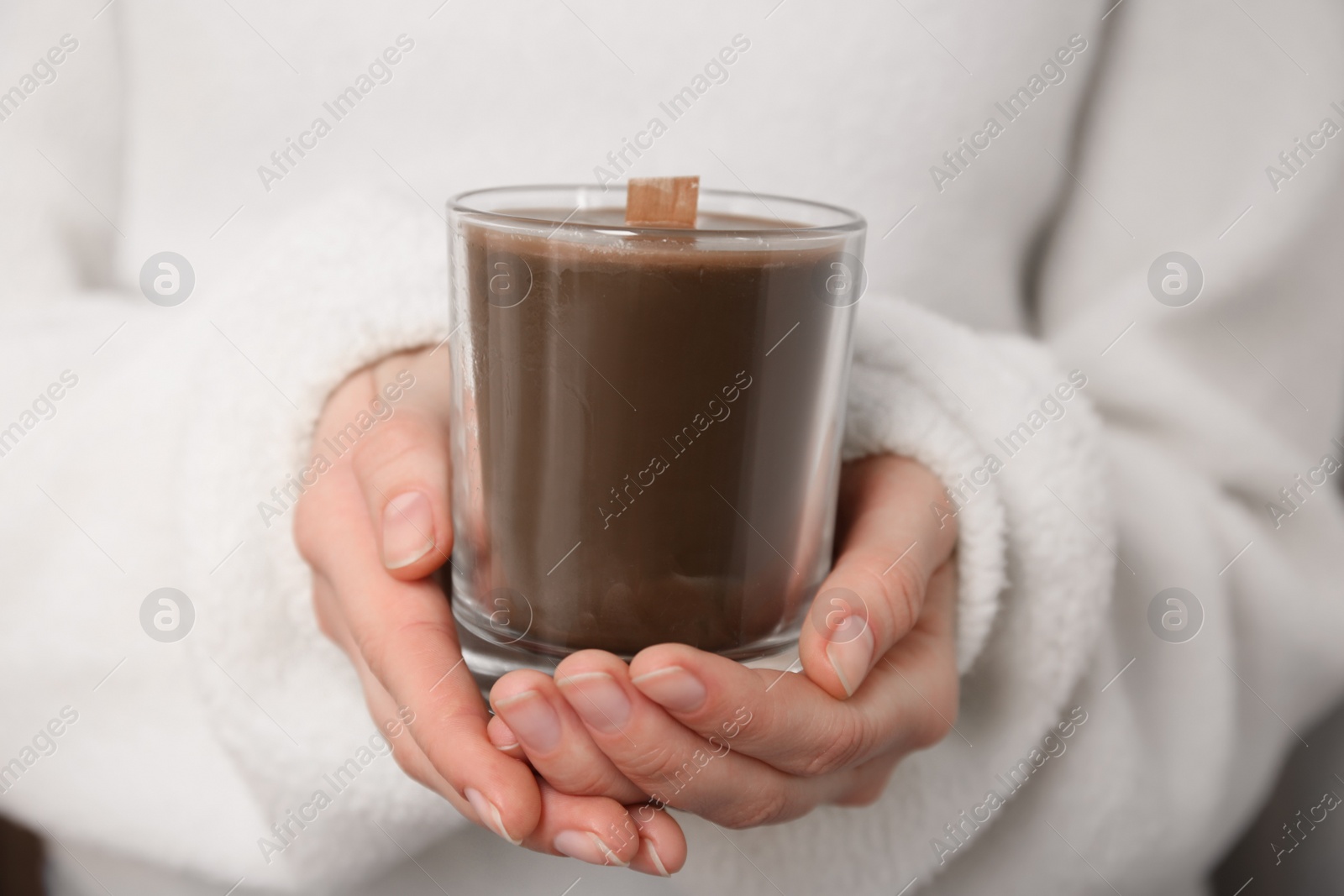 Photo of Woman holding candle with wooden wick, closeup