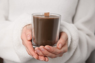 Photo of Woman holding candle with wooden wick, closeup