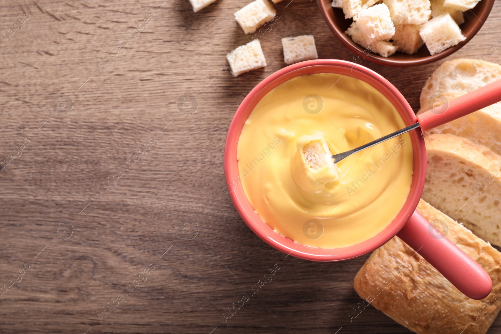 Photo of Flat lay composition with pot of cheese fondue and bread on wooden table, space for text