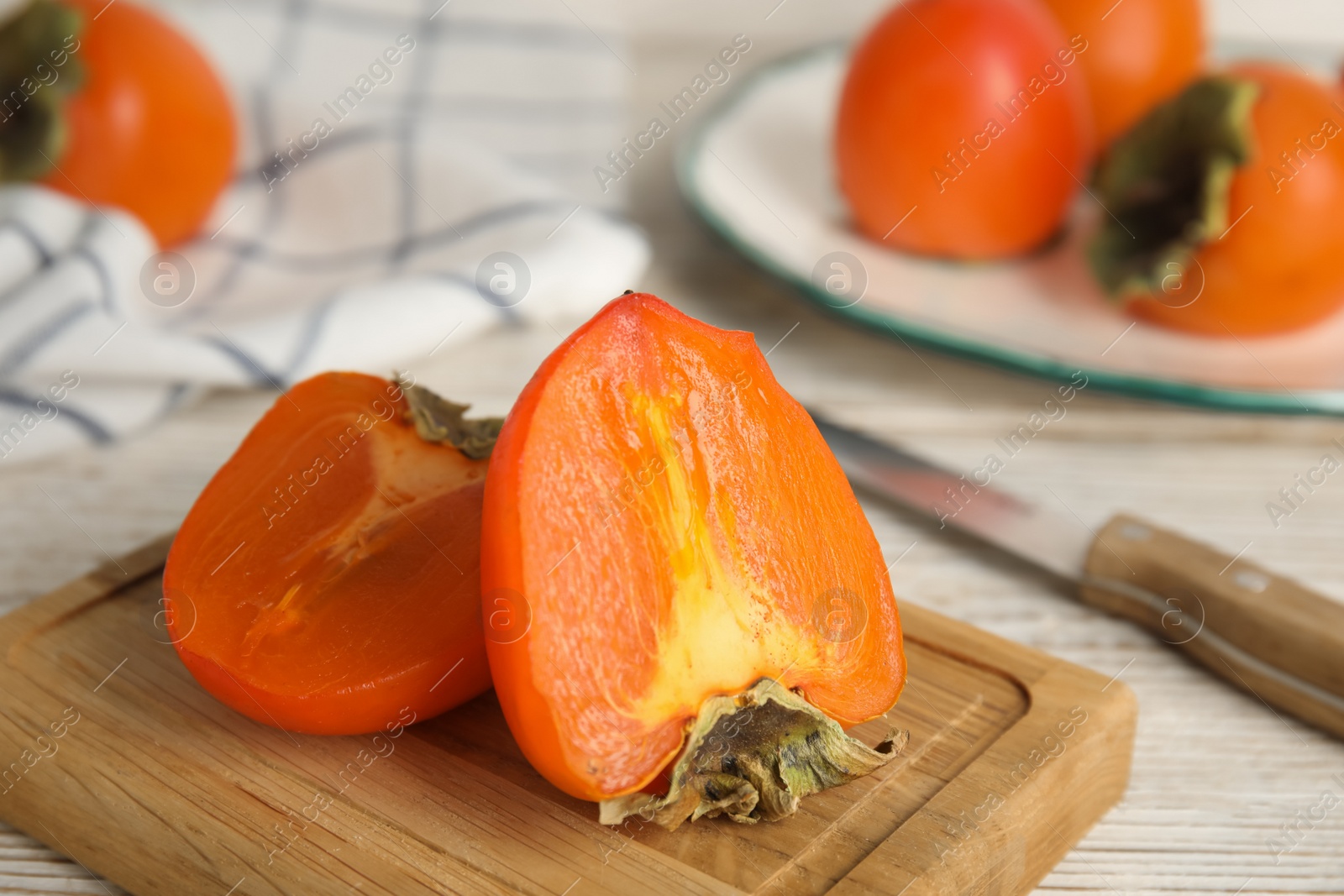 Photo of Tasty ripe persimmon on white wooden table, closeup