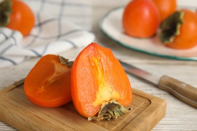 Photo of Tasty ripe persimmon on white wooden table, closeup