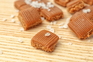 Delicious caramel candies with salt on wooden table