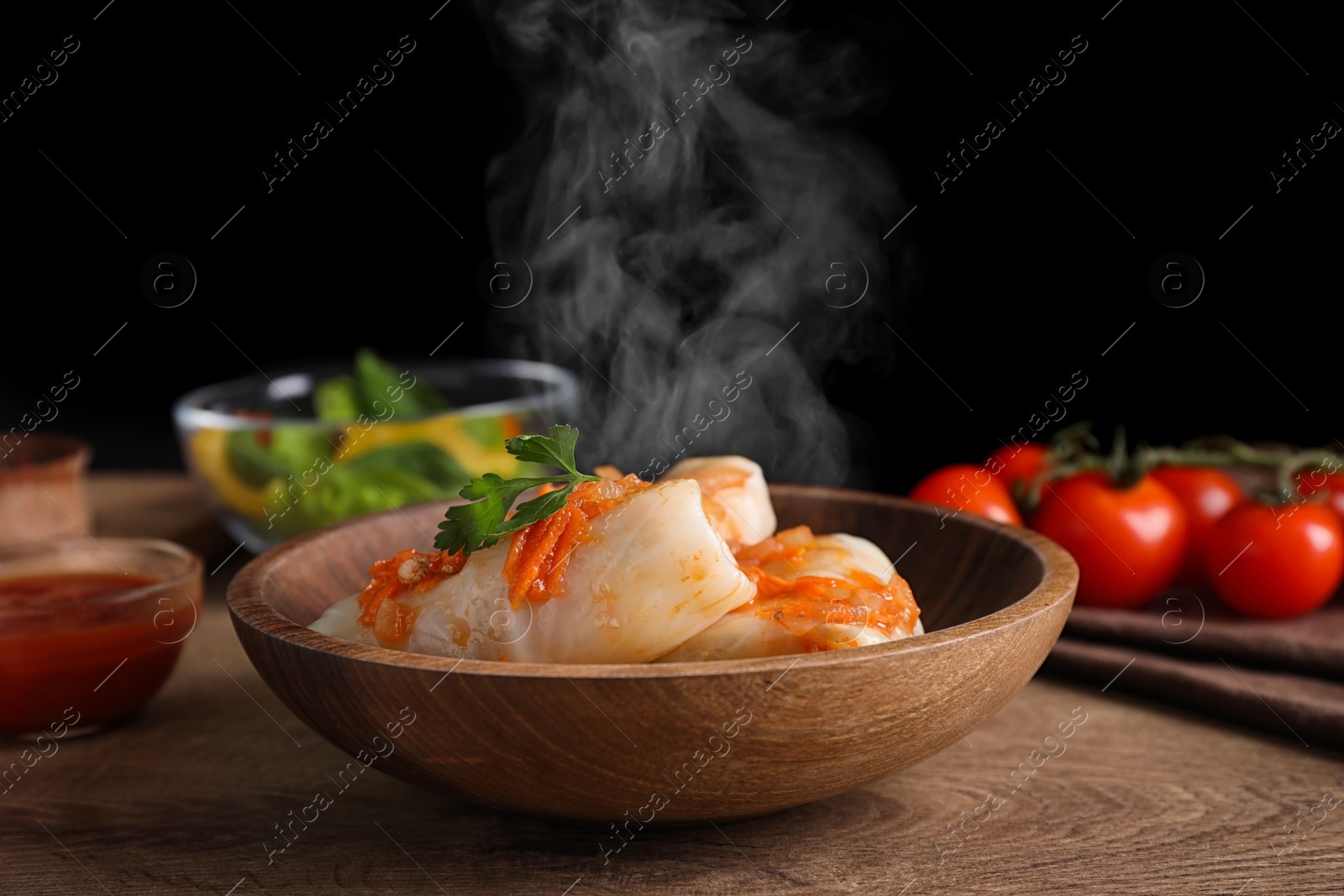 Image of Delicious cabbage rolls served on wooden table against black background