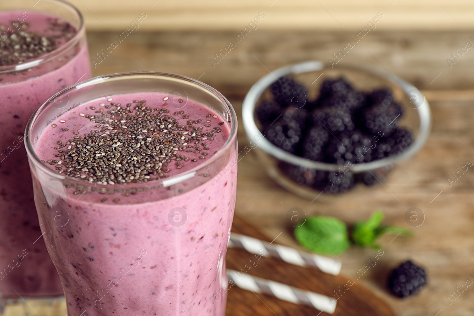 Photo of Delicious blackberry smoothie in glasses on wooden table, closeup. Space for text