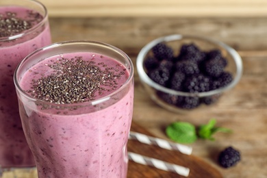 Delicious blackberry smoothie in glasses on wooden table, closeup. Space for text