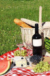 Picnic blanket with delicious food and wine outdoors on summer day