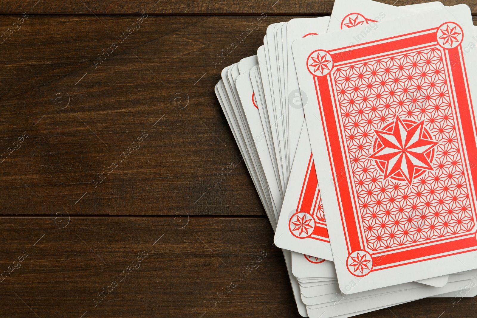 Photo of Deck of playing cards on wooden table, top view. Space for text